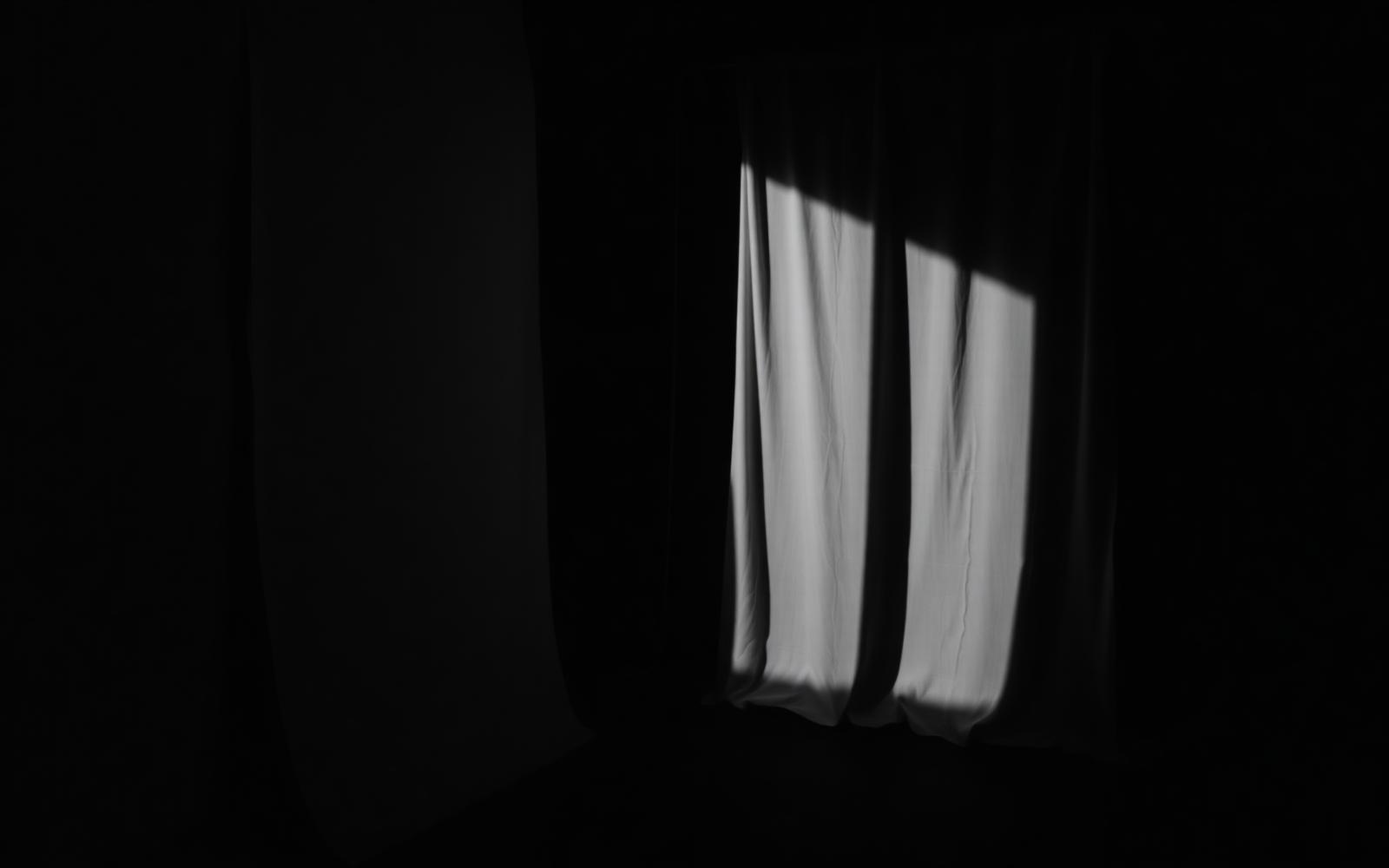 Ivory drapery lit by a shaft of daylight in a dark interior